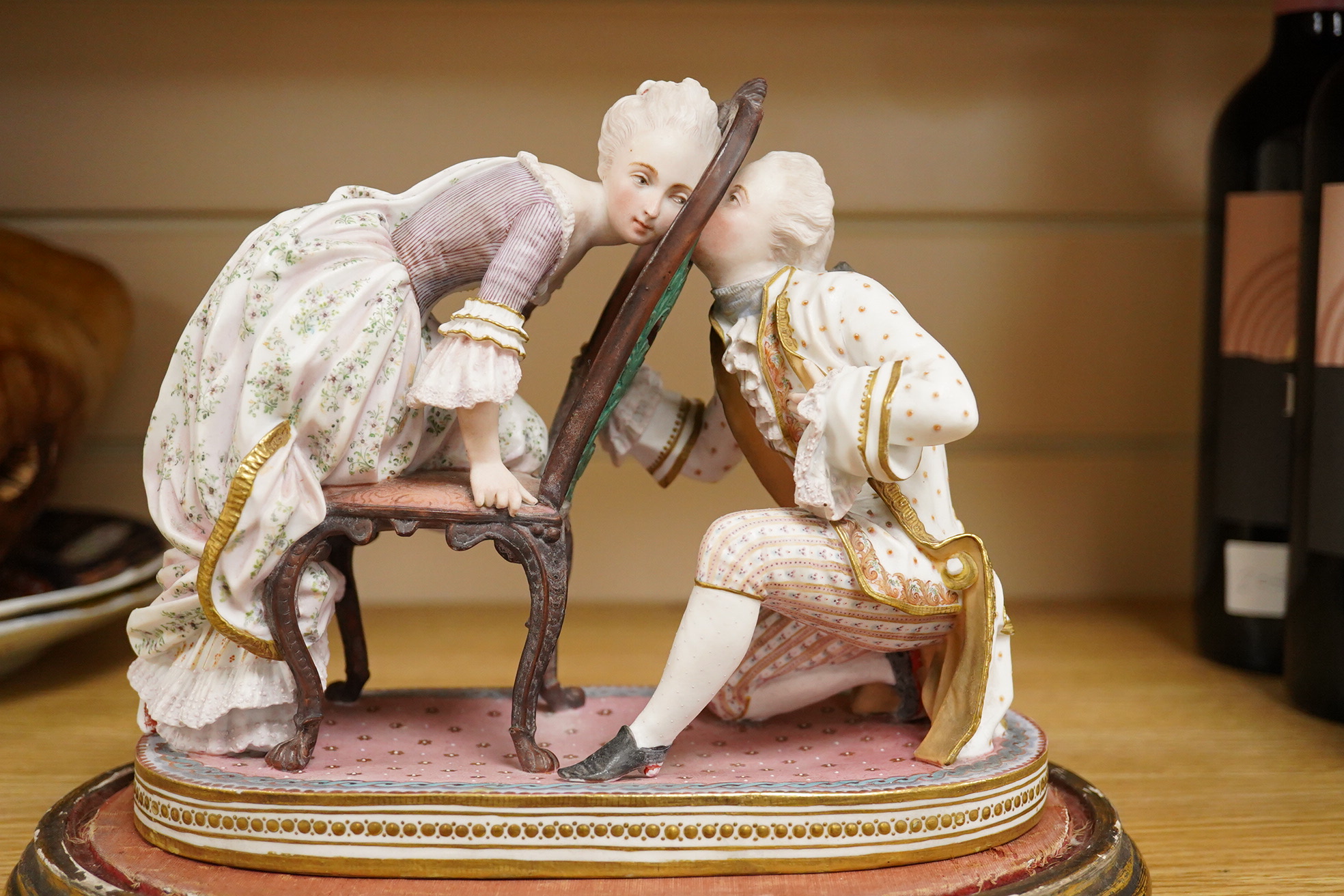 A 19th century biscuit porcelain study of a courting couple under glass dome, raised on gilt base, 28cm high